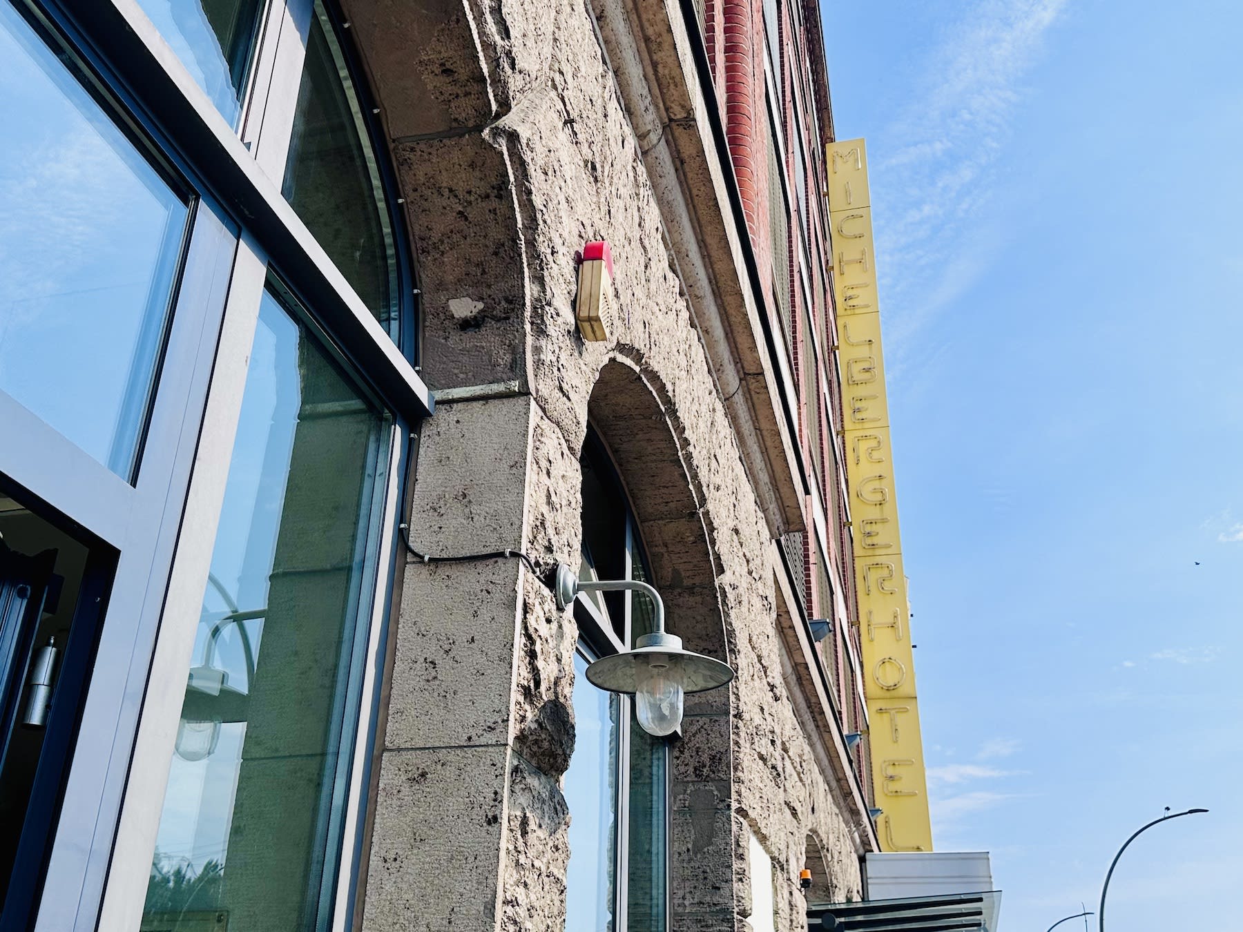 Side view of a brick building in Berlin, featuring a yellow vertical sign reading 'MICHELBERGER HOTEL' against a clear blue sky. This iconic establishment is part of the diverse landscape of gay hotels in Berlin, offering a welcoming atmosphere that reflects the city's vibrant cultural scene and its commitment to inclusivity.
