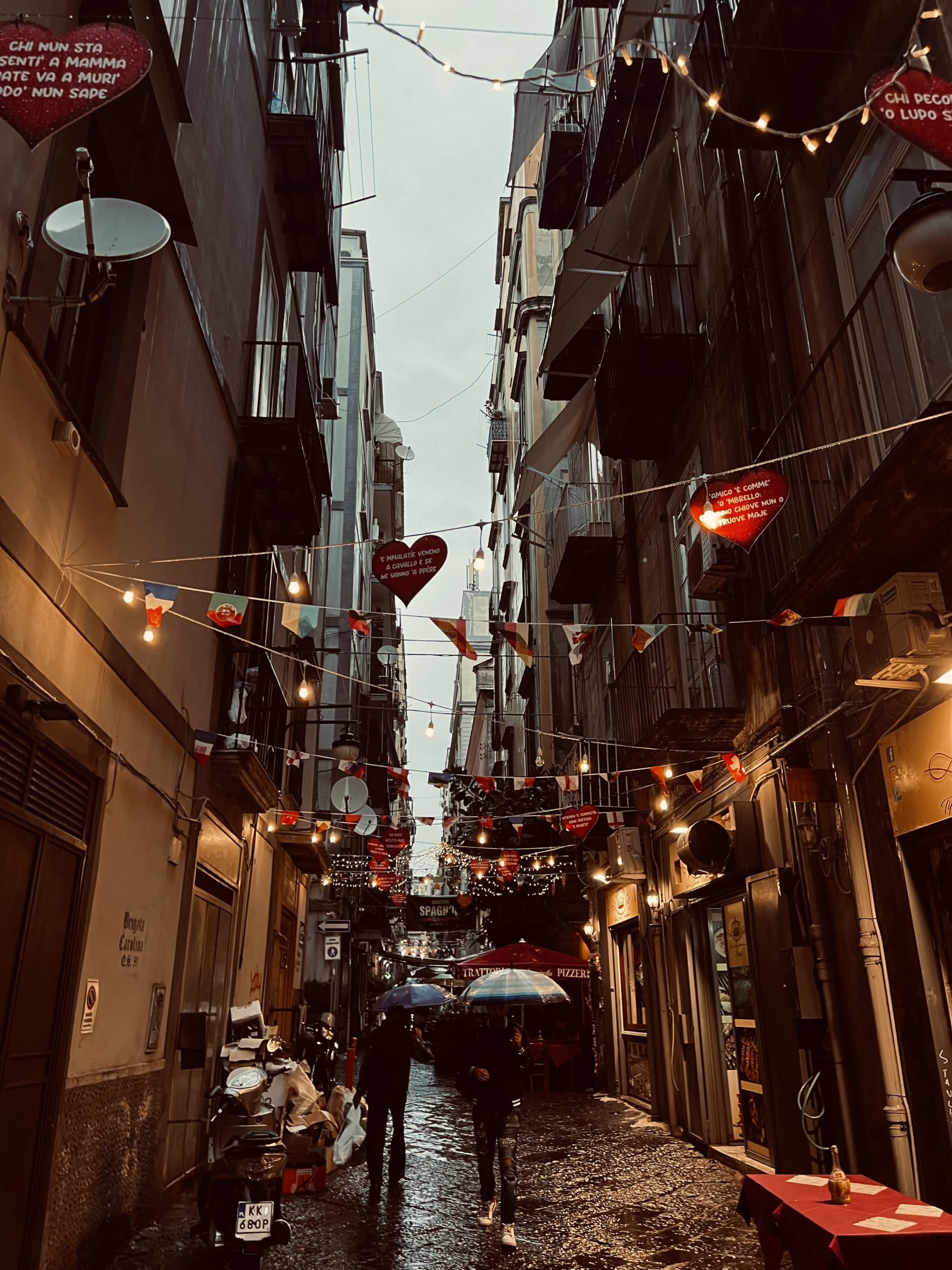 A rainy evening in Naples’ Quartieri Spagnoli, with narrow streets adorned with lights and banners. This atmospheric shot reflects the vibrant nightlife in gay Naples, Italy.