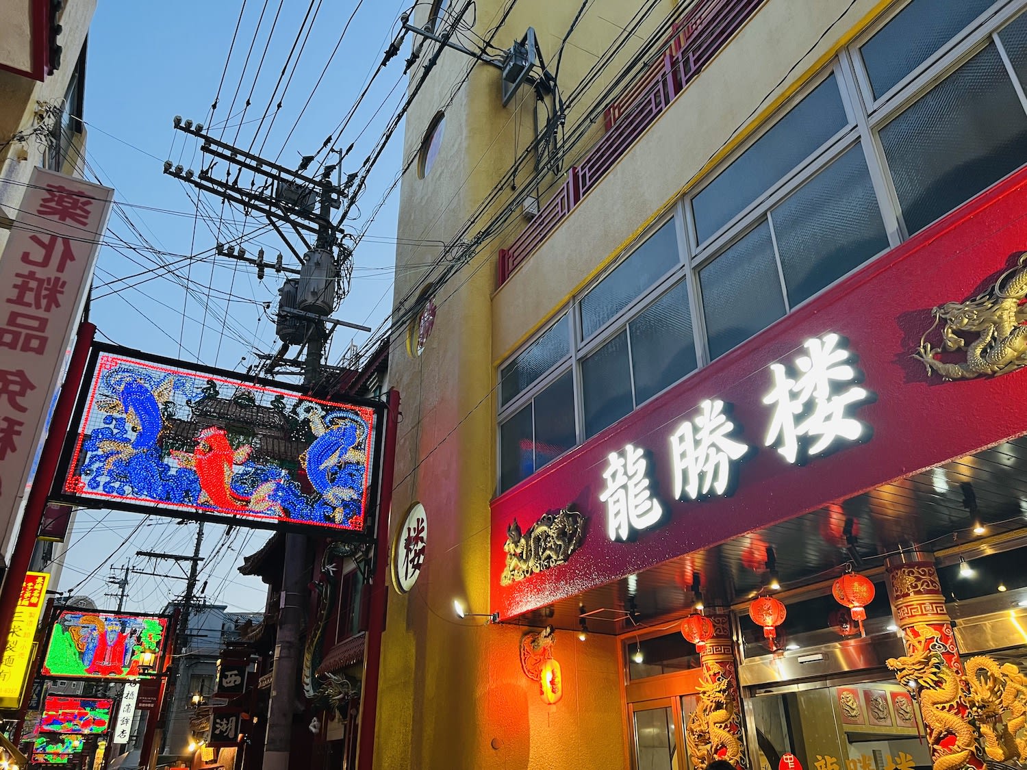 Vibrant street in Nagasaki's China Town with colorful neon signboards featuring traditional Japanese characters and designs, showcasing the city's lively night culture.