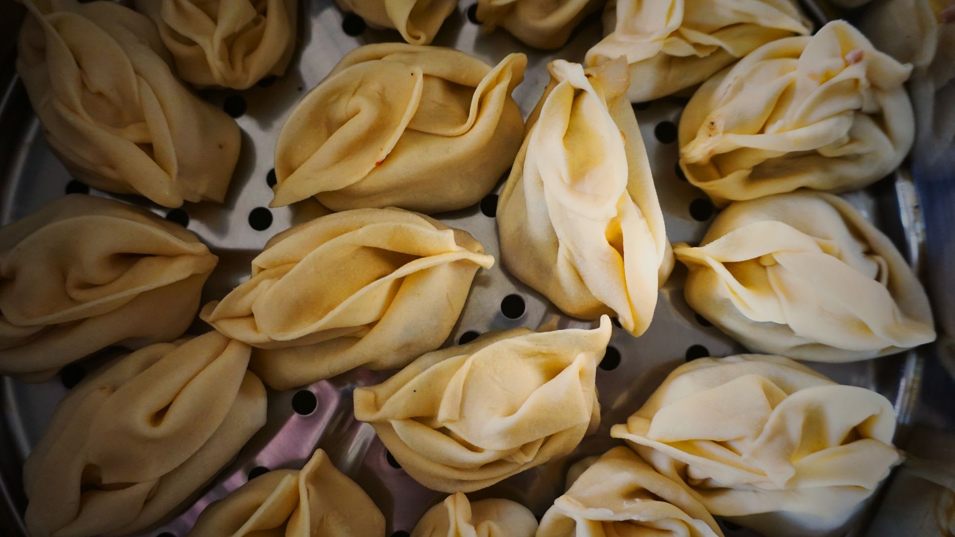 Close-up of traditional Kyrgyz manti, steamed dumplings filled with meat, displayed in a steaming tray, highlighting a popular dish in Bishkek cuisine.