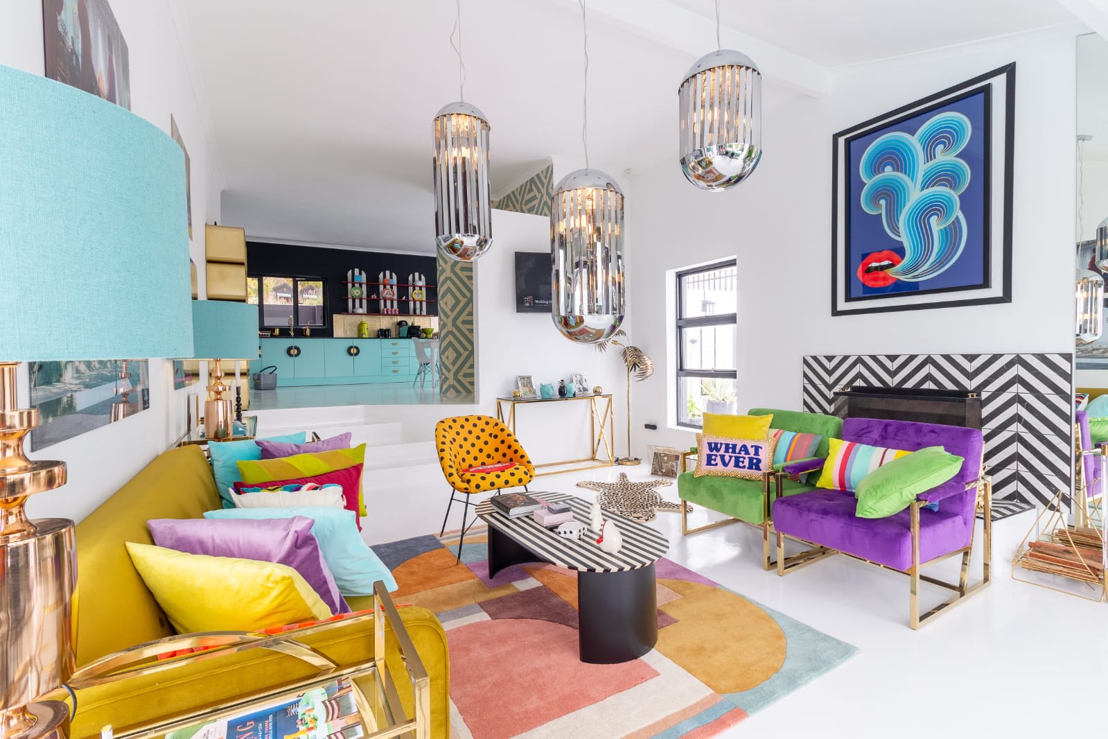 Vibrant living room in gay Cape Town featuring colorful furniture, geometric patterns, and modern lighting. Artwork adorns the walls, mirroring the city's inclusive spirit, much like its diverse LGBTQ+ bars. Visible shelves in the background add to the eclectic charm and reflect a welcoming atmosphere that celebrates diversity.