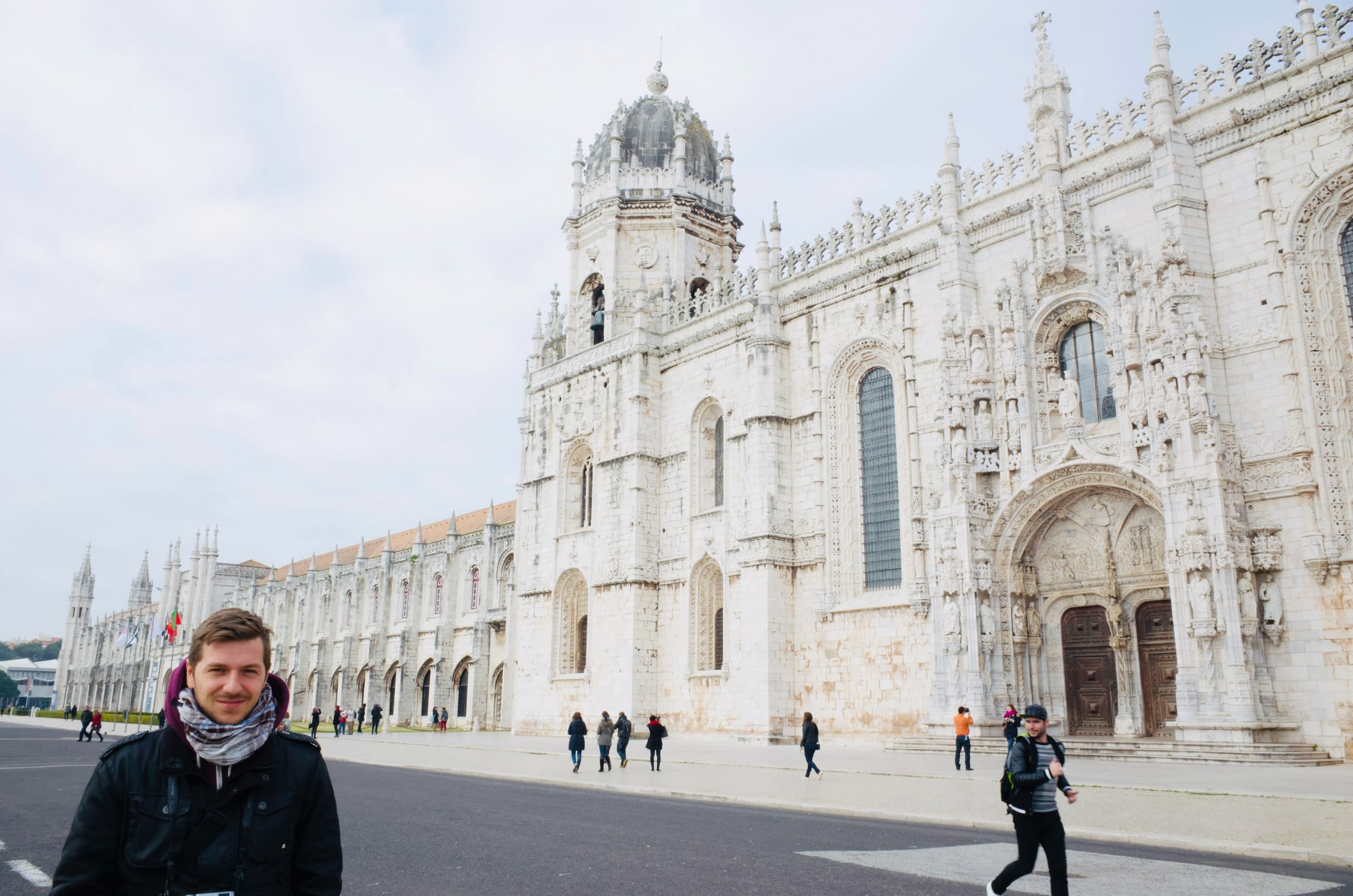 A person standing in front of the magnificent Jerónimos Monastery, highlighting the rich historical heritage of gay Lisbon.
