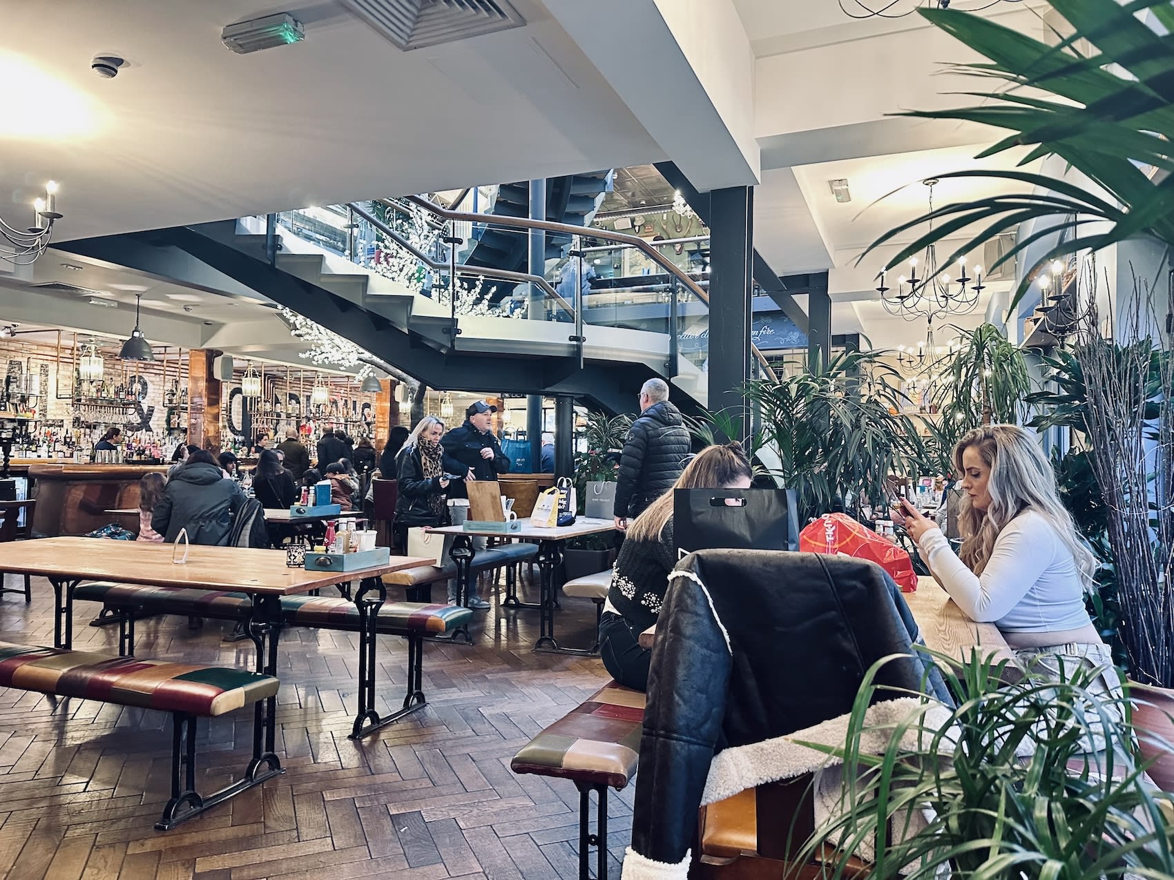 The interior of Hall & Woodhouse in Bath, United Kingdom, featuring a spacious dining area with rustic wooden tables and lush greenery. The pub is a popular gathering spot for the LGBTQ+ community, offering a warm and inviting environment in the city.