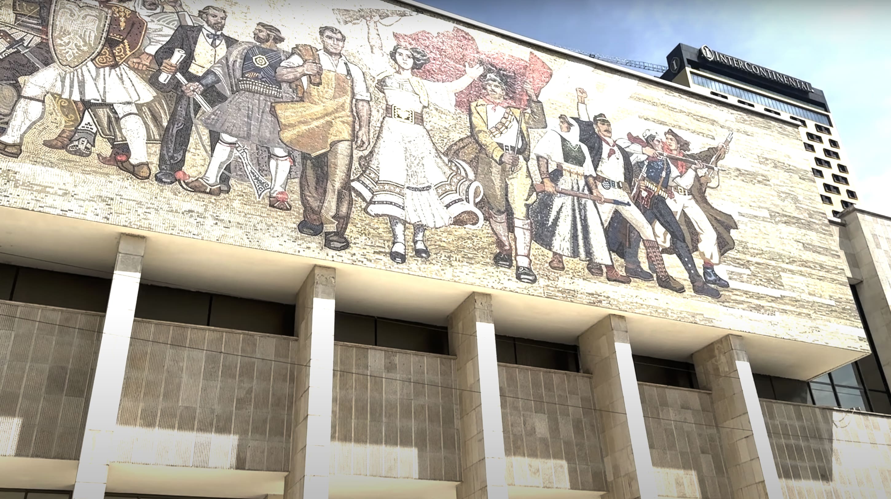 A vibrant mural on a building facade in Tirana, Albania, showcases people in diverse attire involved in various activities. This scene reflects the lively cafes and dynamic atmosphere that are among the delightful things to do in Tirana, capturing the city's essence through art and culture.