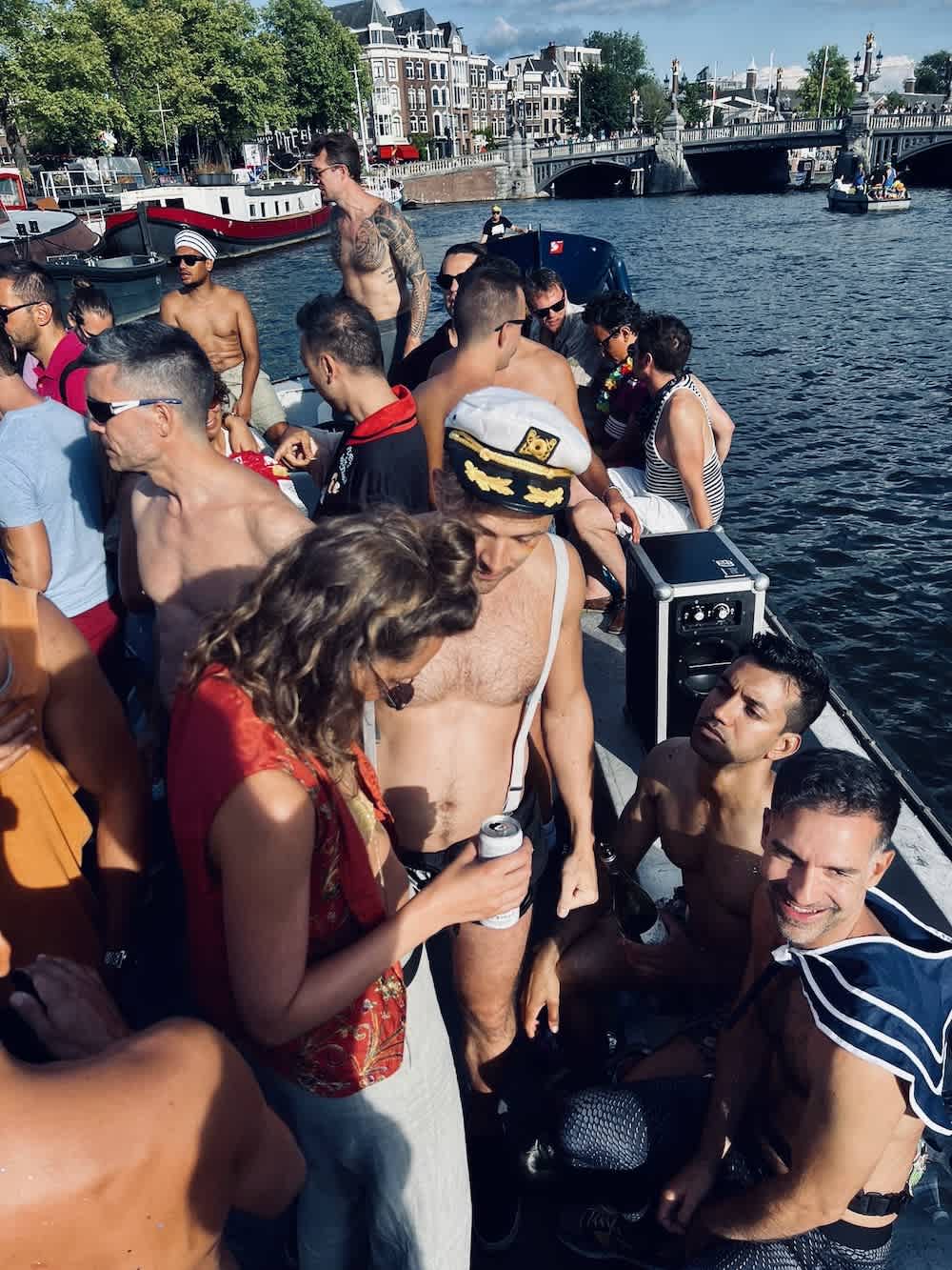 A festive crowd on a boat party, waving and dancing, during a gay pride celebration in Amsterdam, encapsulating the exuberance of the LGBTQ+ community.
