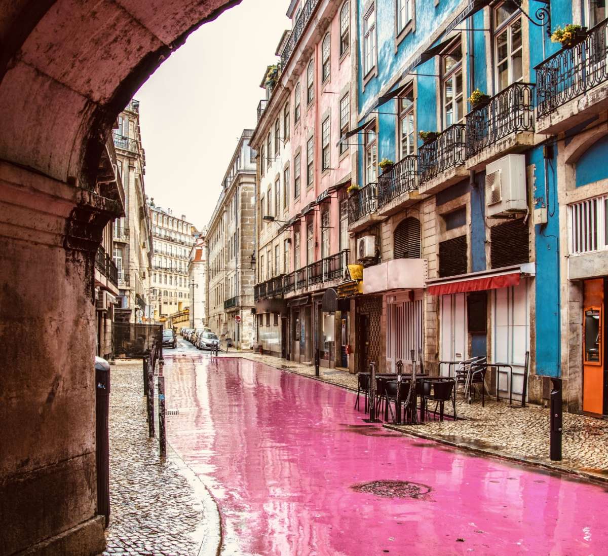 A charming street in Lisbon with colorful buildings and a pink painted road, capturing the lively atmosphere of gay Lisbon.