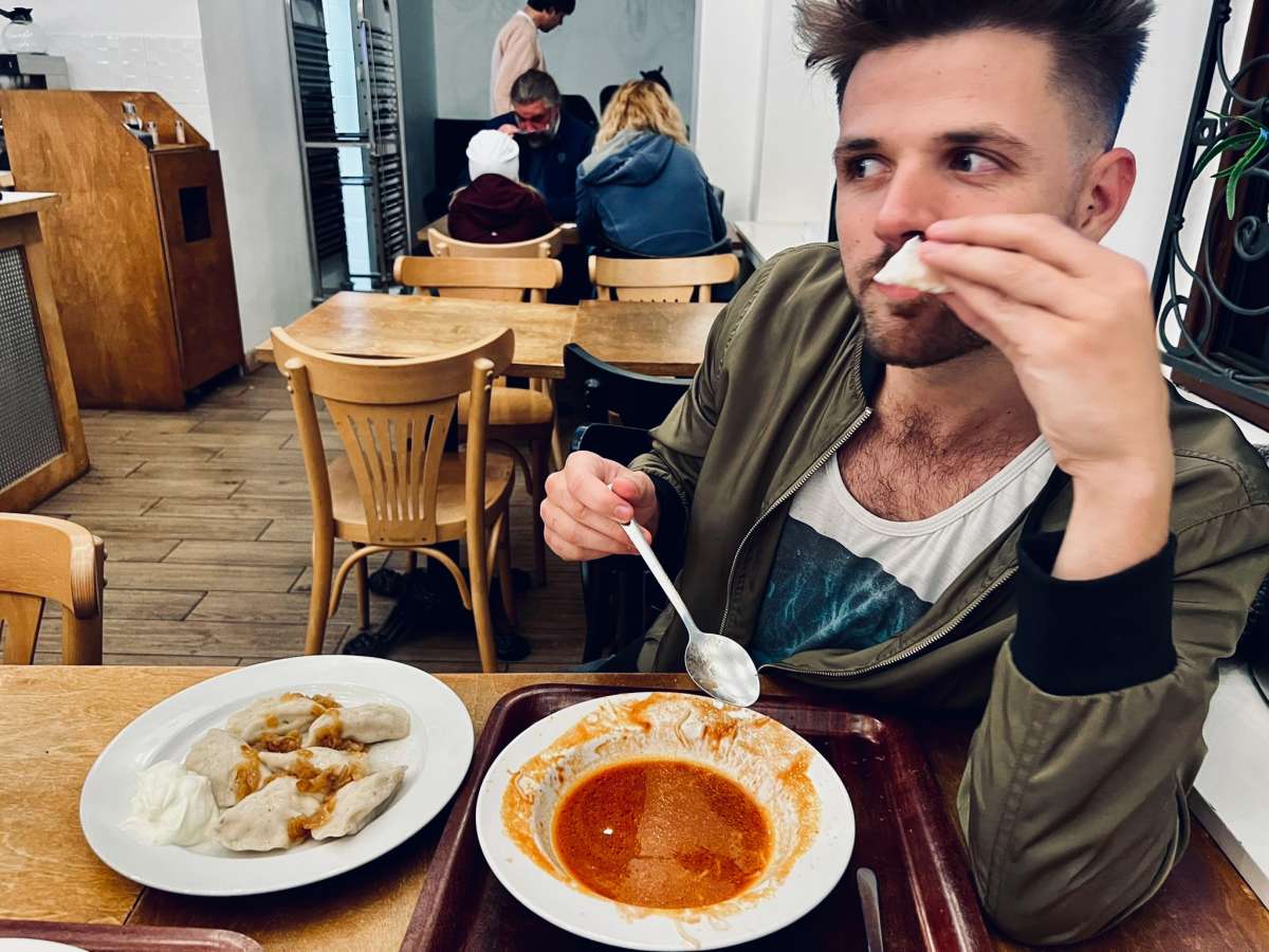 A diner enjoys a hearty meal at a popular milk bar in Warsaw, wiping his mouth with a napkin, with a plate showing remnants of a delicious meal suggesting satisfaction and good appetite.