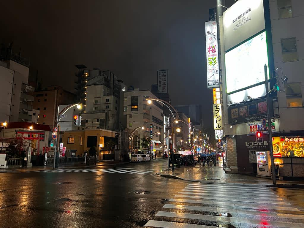 Nighttime view of a bustling street in Sapporo with illuminated signs and archways, capturing the vibrant nightlife of a Hokkaido itinerary.