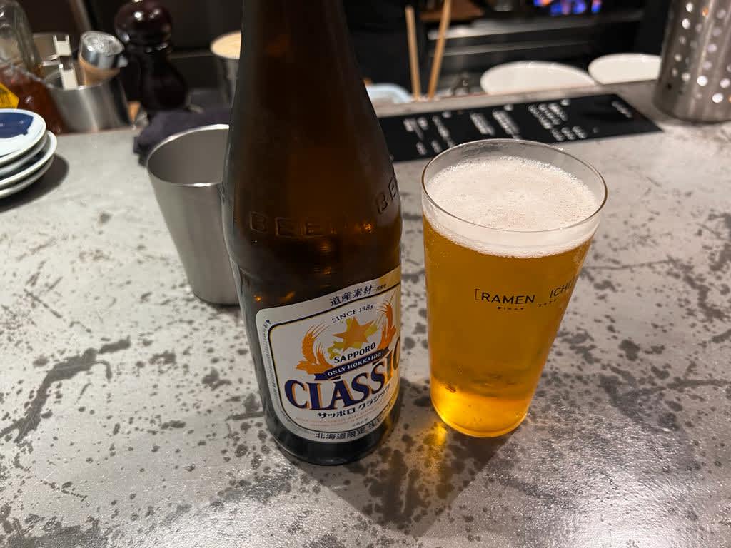 A chilled bottle of Sapporo Classic beer next to a half-full glass on a bar counter, reflecting a casual dining experience in Sapporo, Hokkaido itinerary