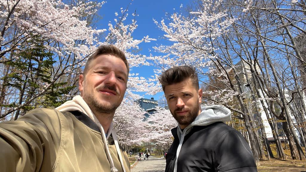 Selfie of two friends with cherry blossoms in Sapporo, capturing the joy of spring during a Hokkaido itinerary.