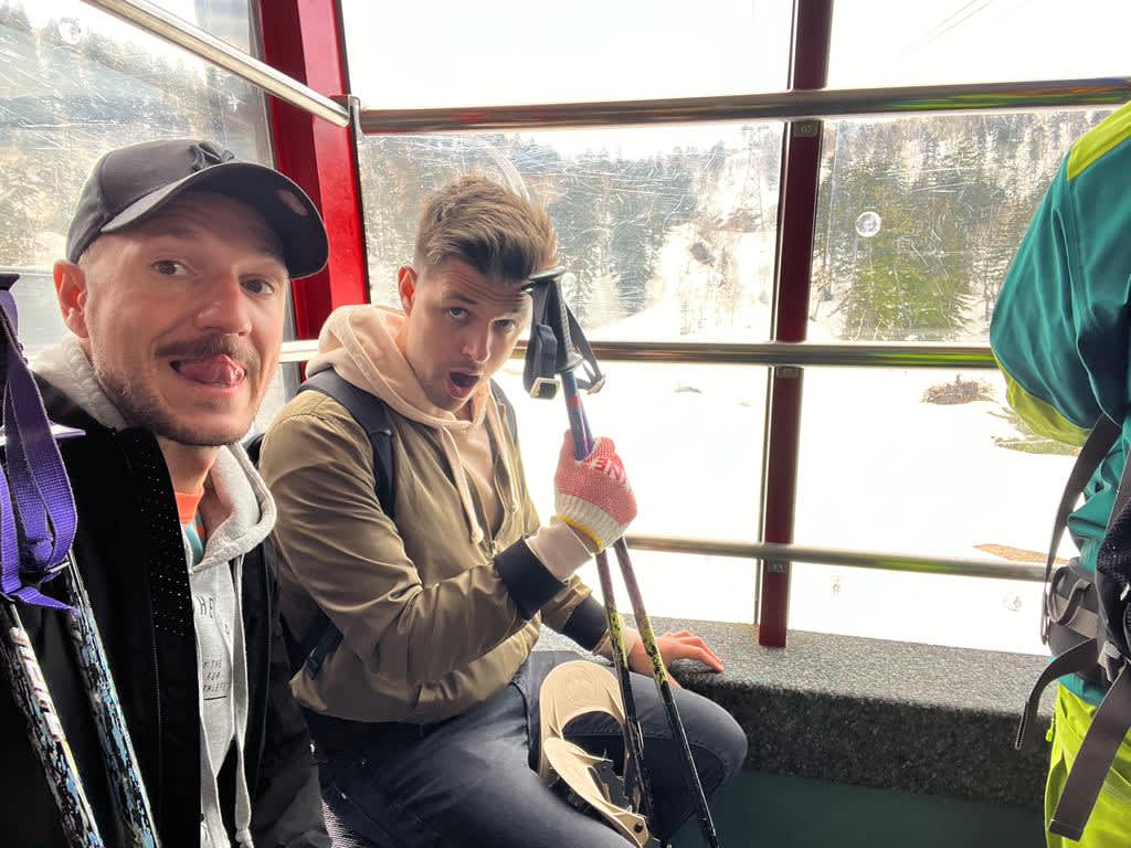 Two friends enjoying a ride on the Mount Asahidake Ropeway with snowy landscapes visible through the window, an adventurous part of a Hokkaido itinerary.