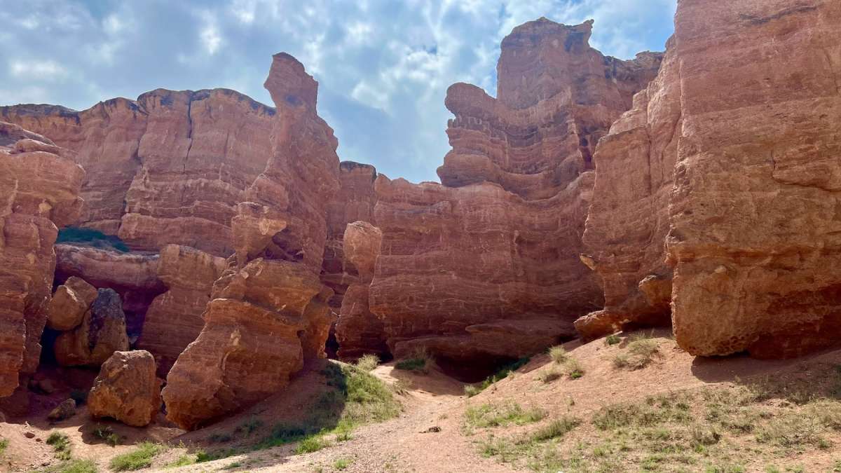 Rugged beauty of Charyn Canyon's striking red sandstone formations under a clear blue sky, a must-visit landmark on a Kazakhstan road trip.