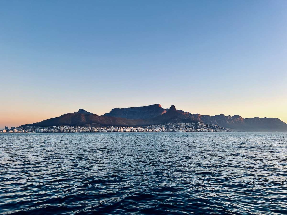 Panoramic view of Table Mountain at sunset, as seen from the water, highlighting the natural magnificence that surrounds gay Cape Town.