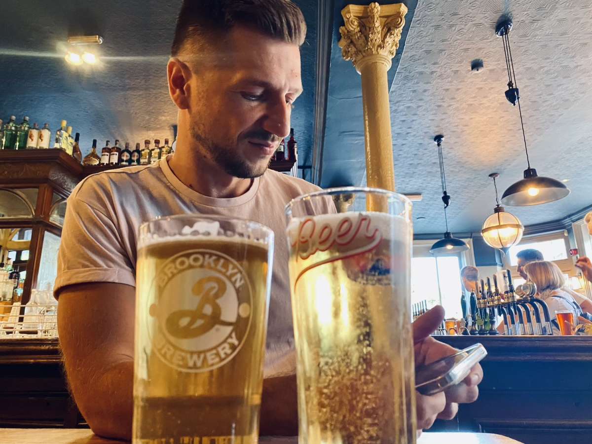 A man enjoying a pint of beer at a traditional London pub, a common social scene in Gay London.