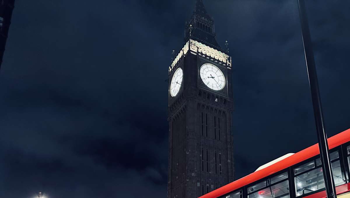 Big Ben illuminated against a night sky with a London bus in the foreground, an iconic representation of Gay London's historic landmarks.