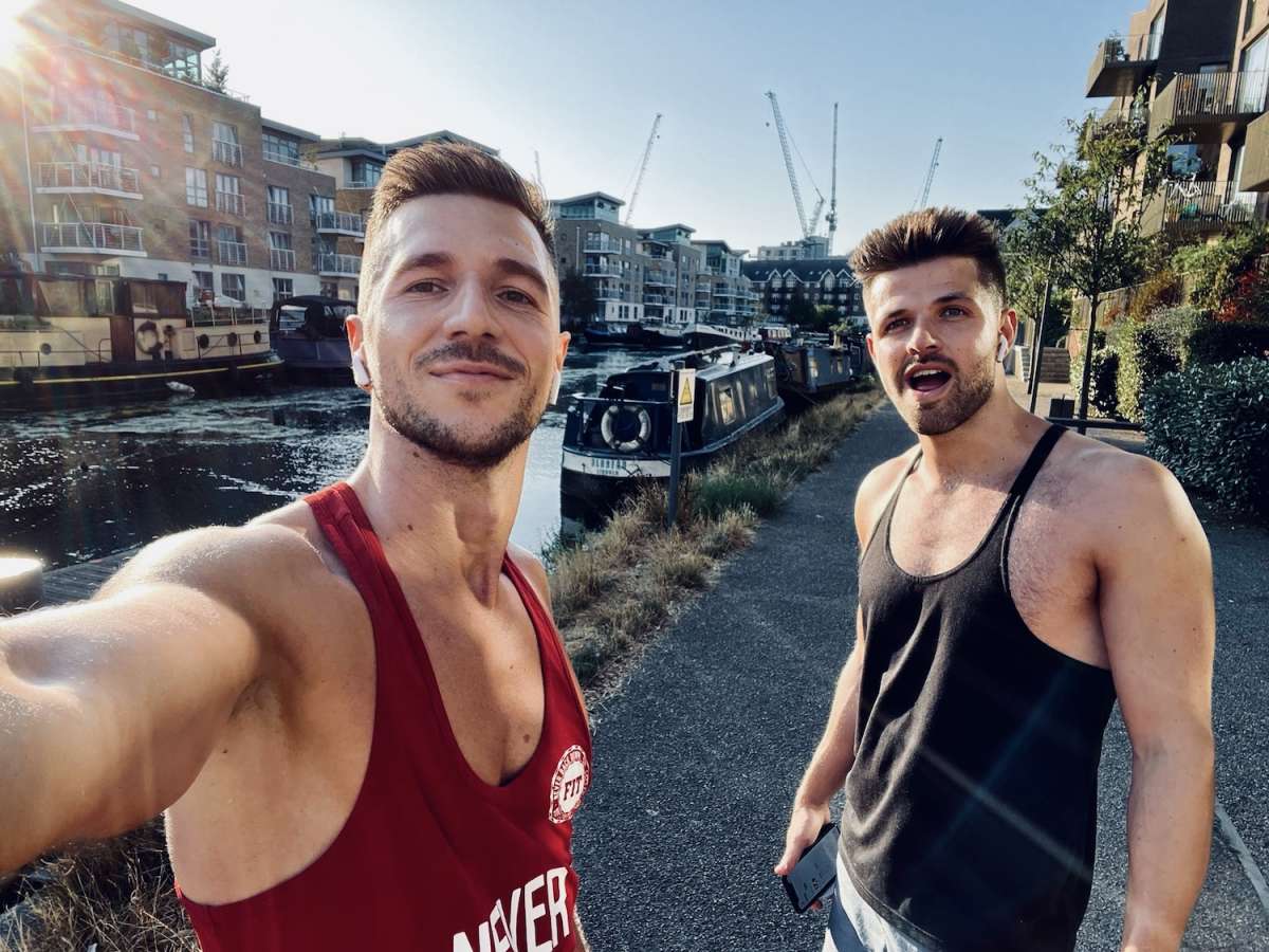 Two friends taking a selfie on a sunny day by London's canals, exemplifying the active and sociable lifestyle within the Gay London scene.