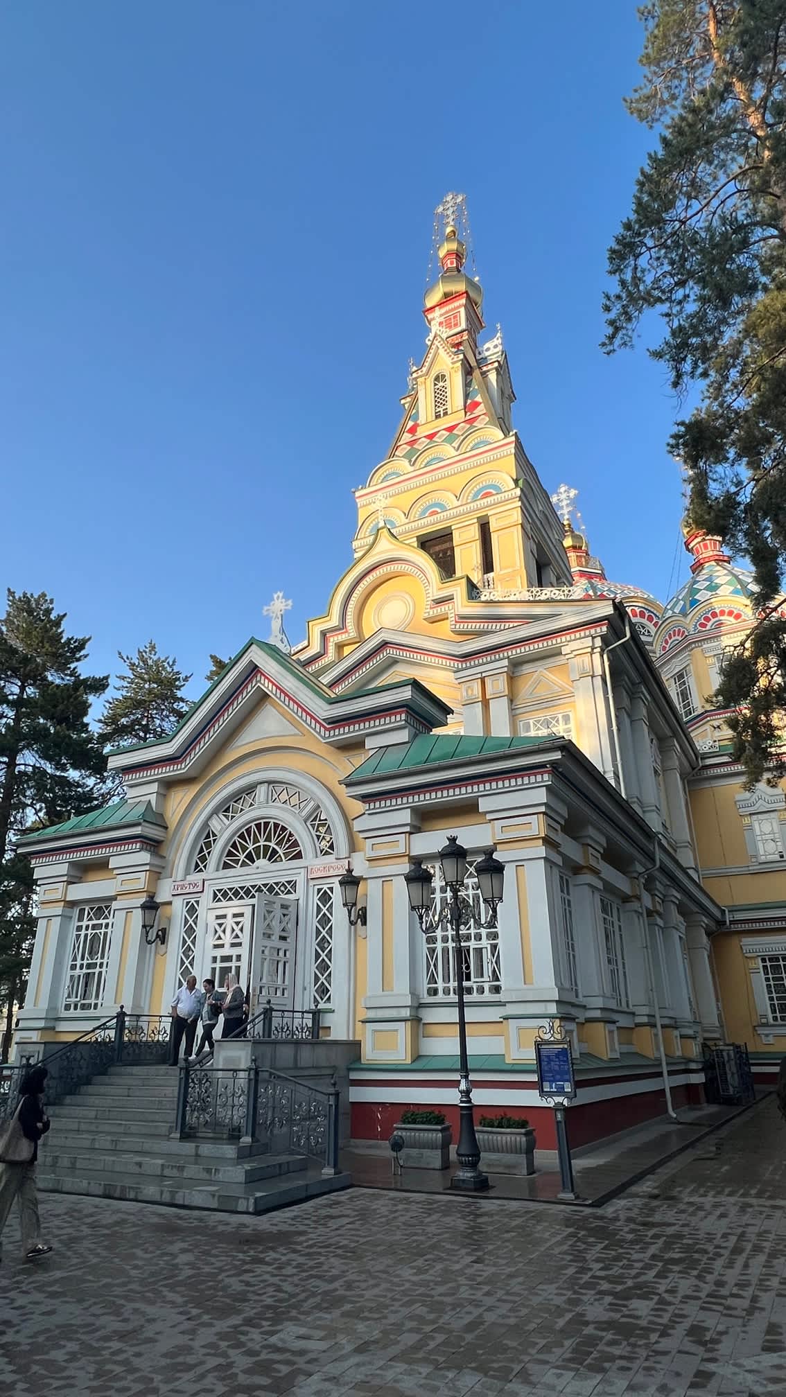 The Ascension Cathedral in Almaty, Kazakhstan, with its bright, multicolored facade and ornate architecture, set against a clear blue sky.