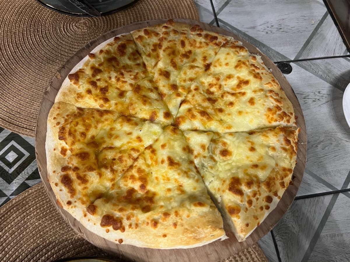 Delicious Georgian khachapuri, a cheese-filled bread, served on a wooden board, representing Almaty's diverse culinary influences.