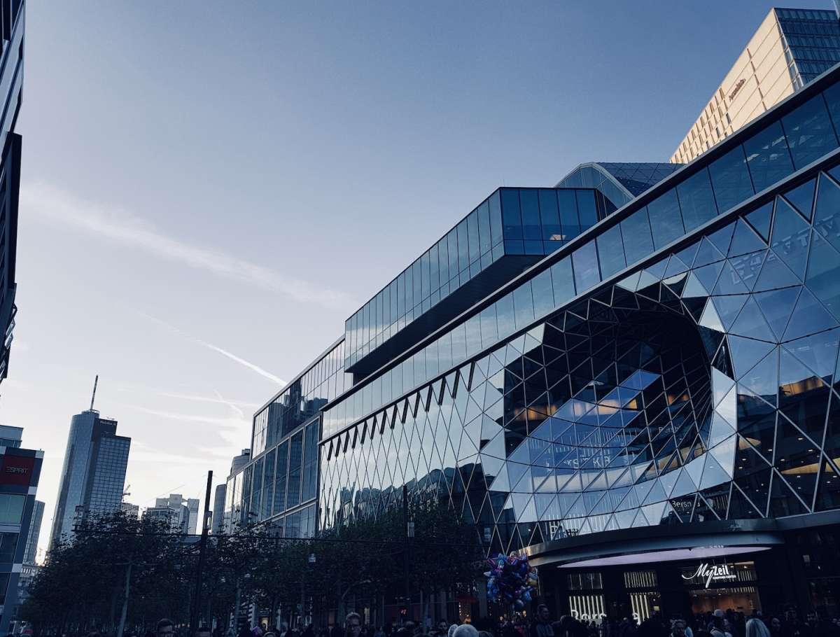 Modern architecture in gay Frankfurt with MyZeil shopping mall's distinctive geometric glass façade against a clear blue sky.