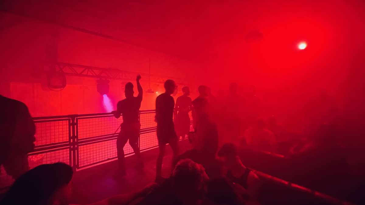 Silhouettes of people dancing under red lights at Adonis club, creating an energetic atmosphere at one of London's best gay clubs.