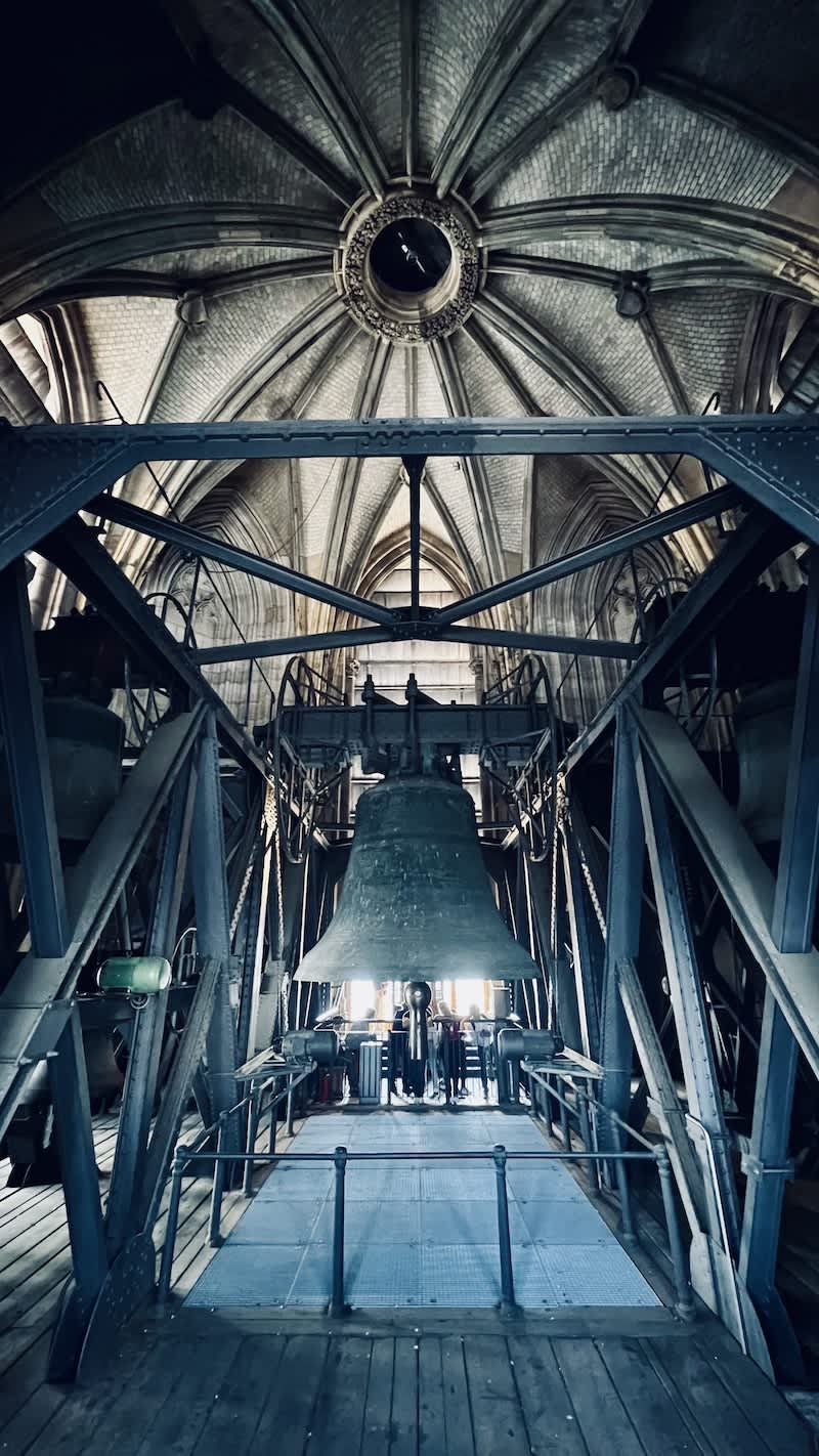 Interior view of the Cologne Cathedral's bell tower, showcasing its intricate gothic architecture and the largest bell, with the keyword 'best restaurants Cologne' suggesting a potential cultural dining experience nearby.