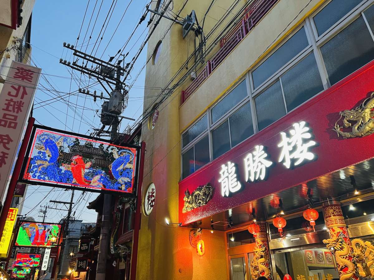 Vibrant street in Nagasaki's China Town with colorful neon signboards featuring traditional Japanese characters and designs, showcasing the city's lively night culture.