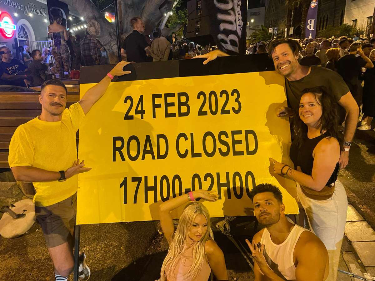 Five friends in front of a road closure sign at a street party in gay Cape Town