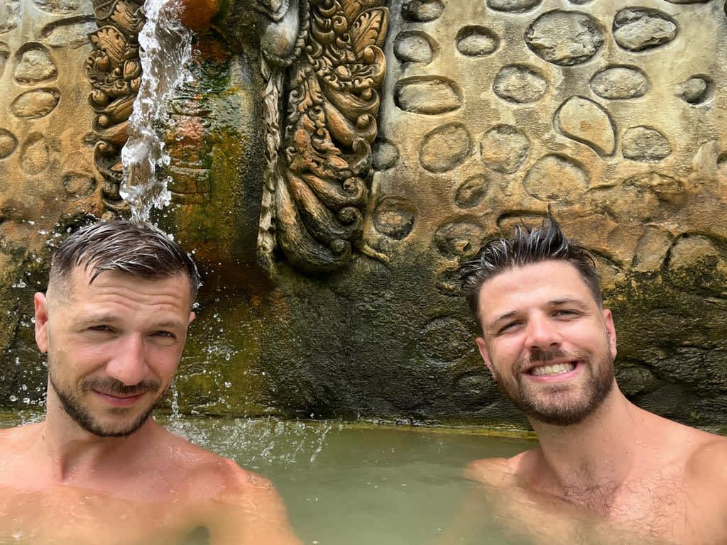 Digital nomads enjoying the therapeutic waters of Banjar Hot Springs in Bali, highlighting the lifestyle perks of living and working remotely in Indonesia.