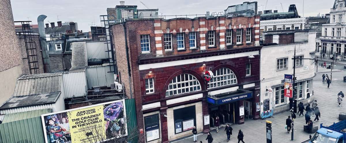 View from above of Camden Town Tube station in London, surrounded by typical British architecture and bustling with pedestrians, capturing the urban vibe of the Camden area.