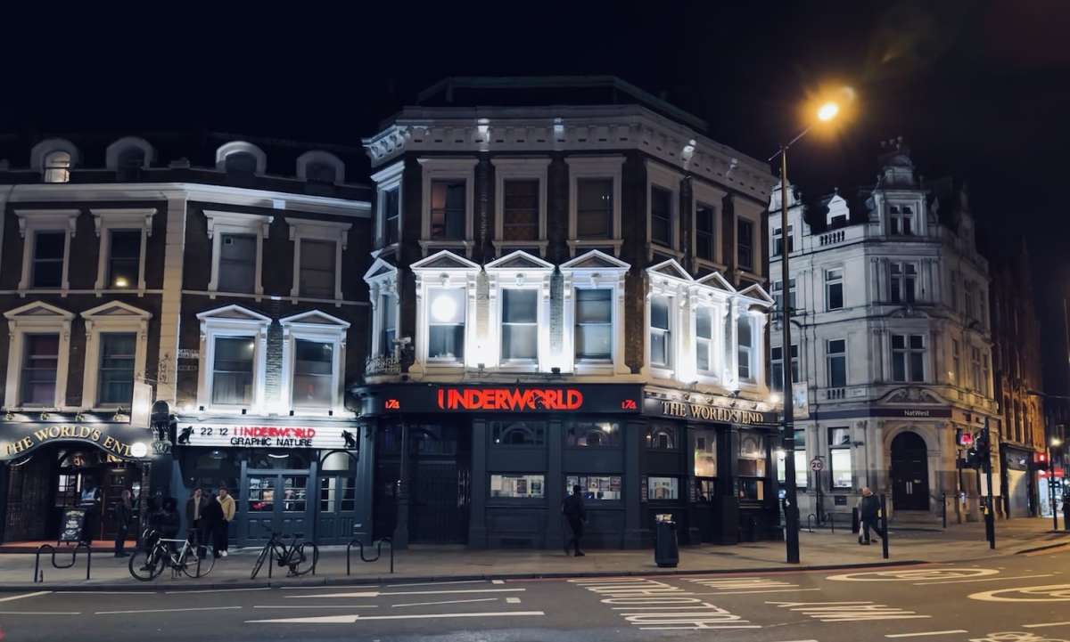 Nighttime exterior of The World's End pub in Camden, London, illuminated by bright lights with its distinctive facade, a popular local landmark known for its lively nightlife.