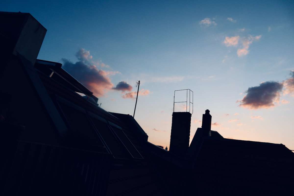 Silhouette of a Berlin cityscape at dusk with roofs, antennas, and a clear sky, portraying an alternative and serene side of Berlin.