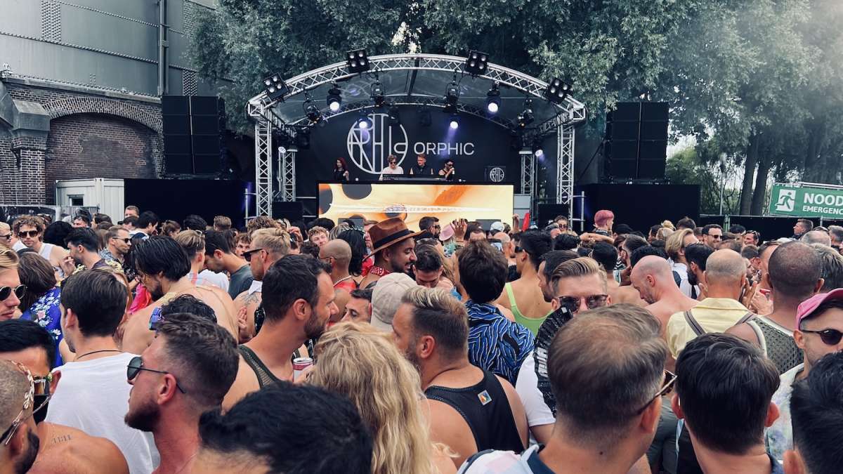 Crowd of festival-goers enjoying a performance at the Milkshake Festival Amsterdam, with a DJ on stage and vibrant stage lighting, embodying the energetic and inclusive spirit of the event.