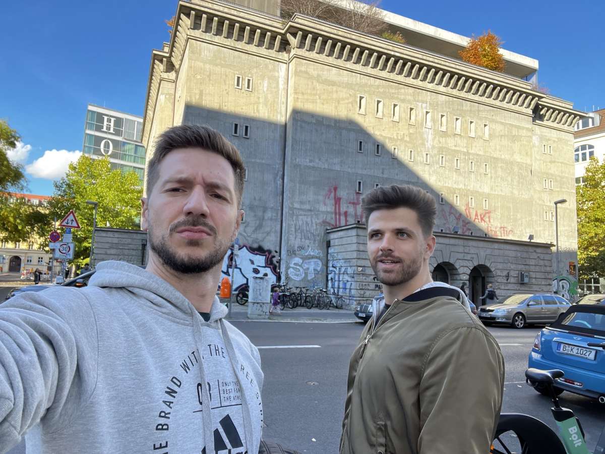 Two men taking a selfie in front of the graffiti-covered Boro Sammlung in Berlin, capturing a moment of urban exploration in an alternative cultural hotspot.