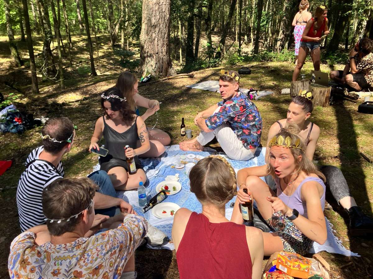 A scenic picnic by the banks of Krumme Lanke in Berlin, with a group of young adults enjoying food and drinks in a forest setting, showcasing an alternative leisure activity in Berlin.