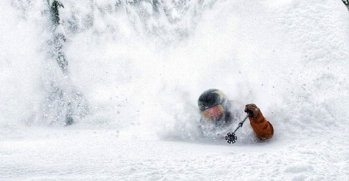 a skiier skiing through sholder high powder