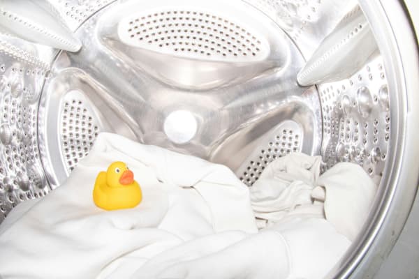 A yellow rubber duck sat in the drum of a washing machine.