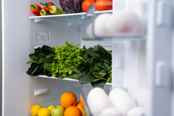 The interior of a fridge full of fruit, vegetables and eggs.