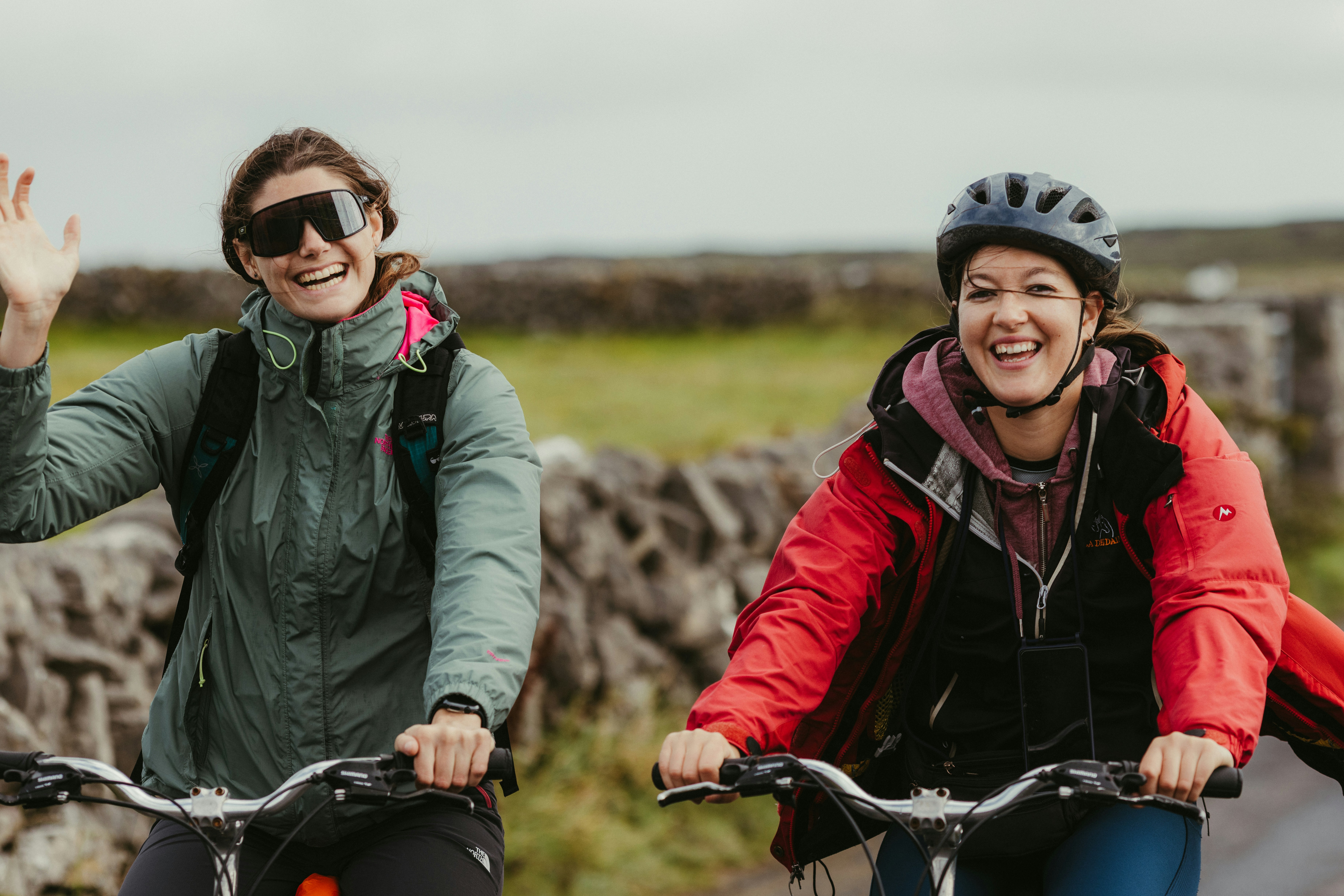 Two ladies riding bikes and having a laugh together