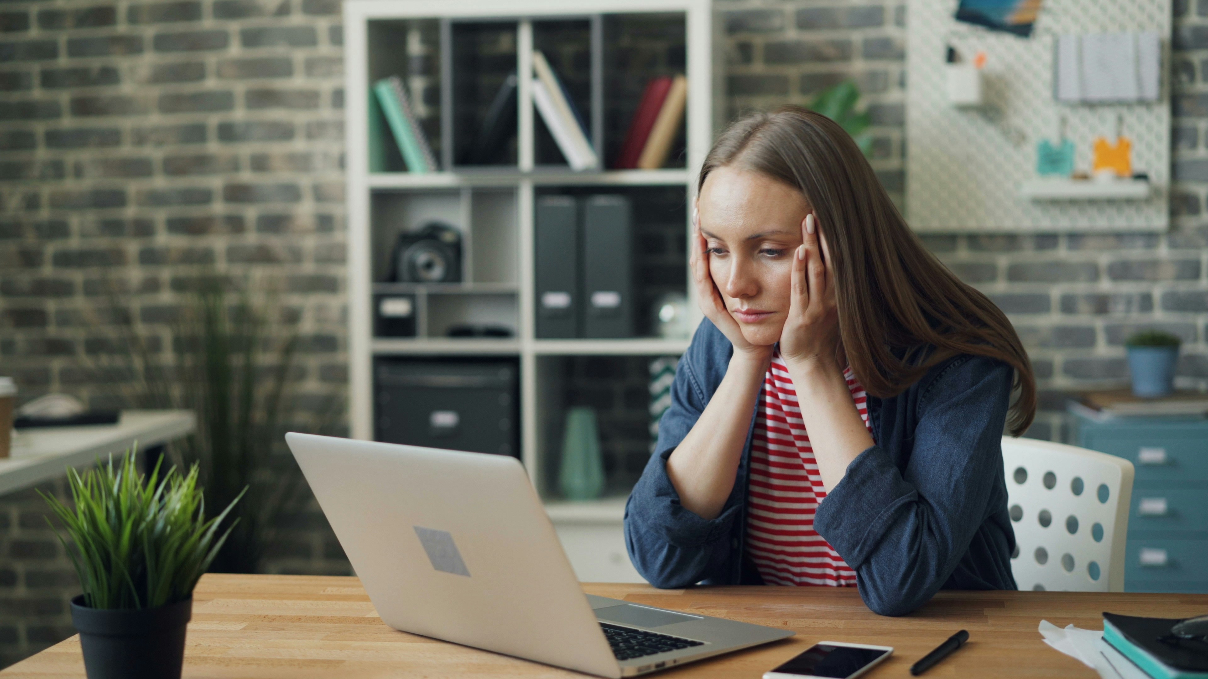a lady sat in front of a laptop looking stressed.