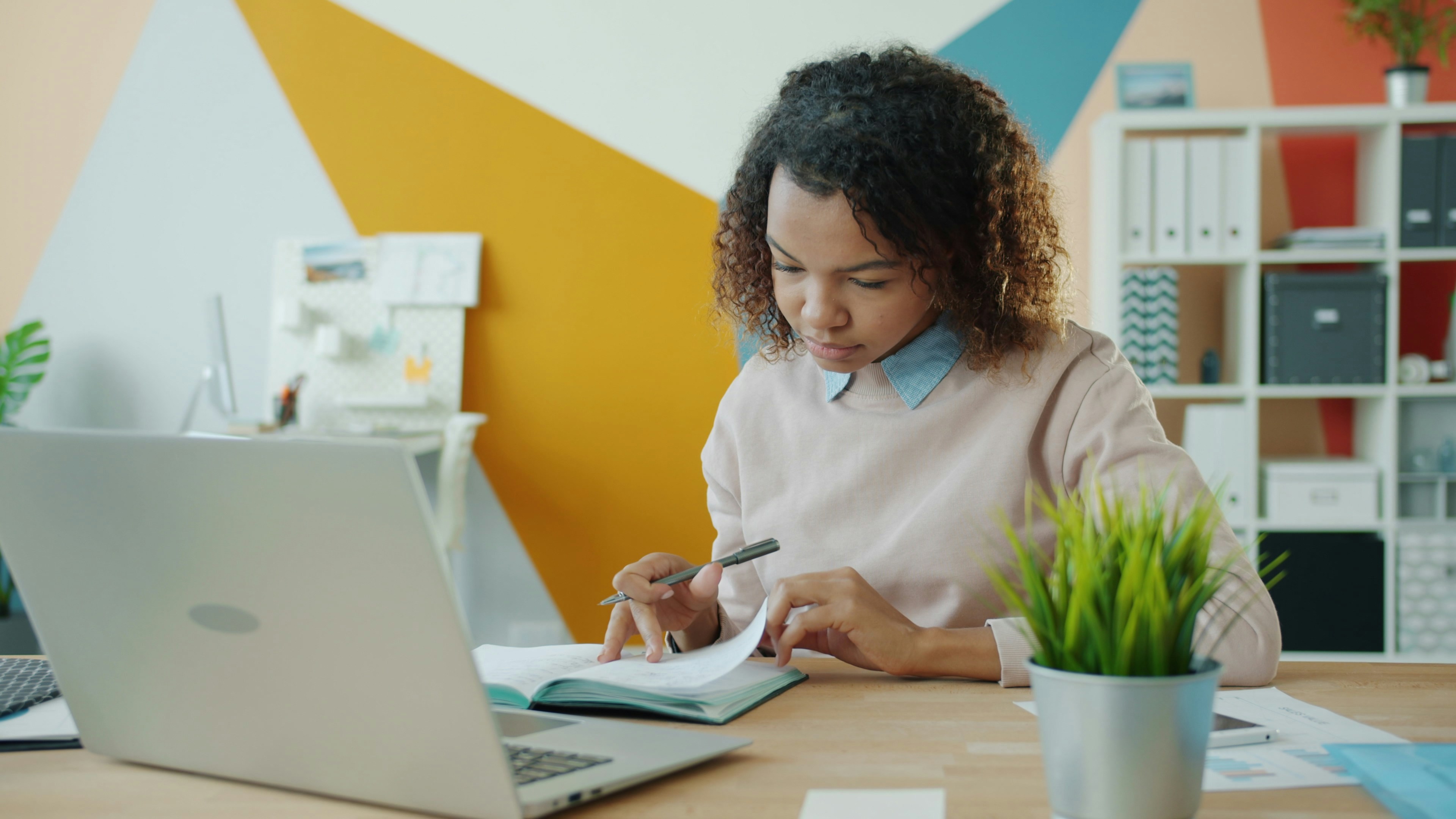 lady looking at a notebook with a laptop in front of her