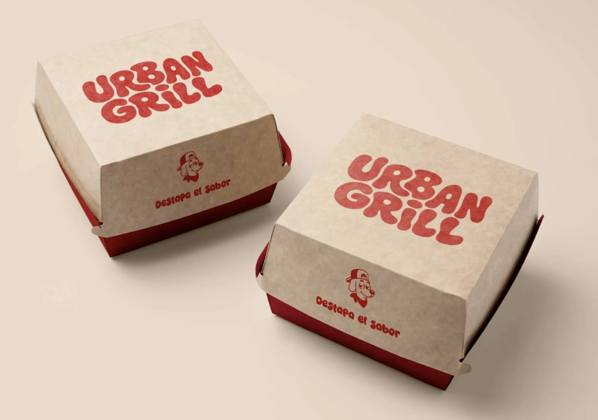 Dos cajas de hamburguesa de Urban Grill en kraft y rojo con el logotipo estampado, de Andrea Jurado, alumna de Diseño Gráfico y Motion Graphics en TRAZOS