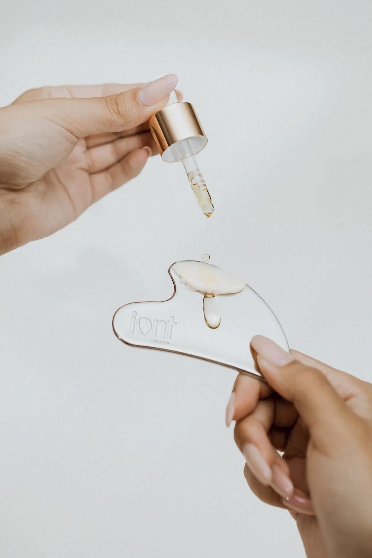 Herramienta gua sha de la marca iont con gotas de sérum, de Rita García, alumna de Diseño Gráfico y Motion Graphics en TRAZOS