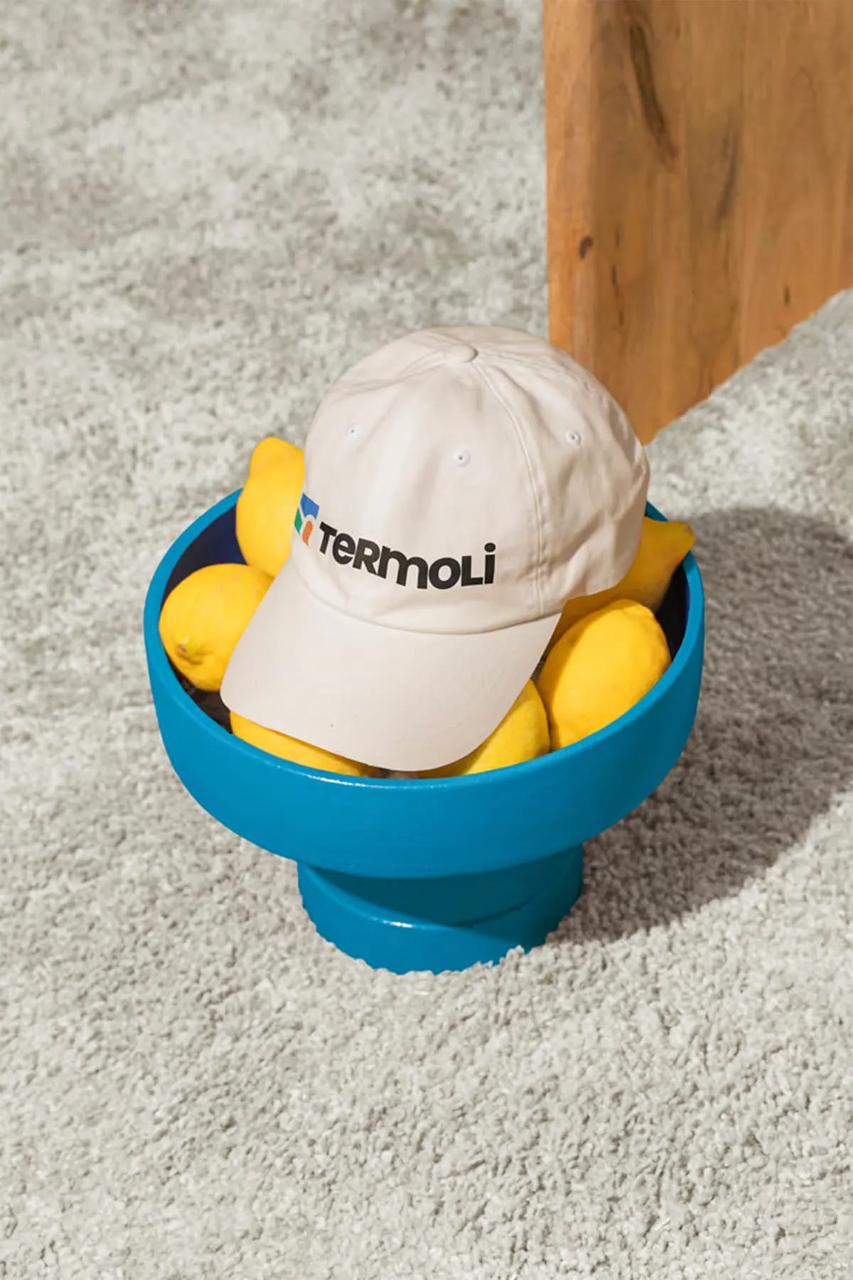 Gorra con la marca Termoli en un cuenco azul con limones, de Belén Gonzalo Antón, alumna de Diseño Gráfico y Motion Graphics en TRAZOS