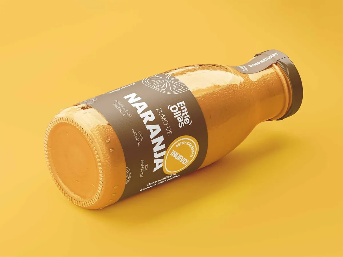 Botella de zumo de naranja de la marca Entre Ollas con etiqueta oscura sobre fondo amarillo, de Marina Gabilondo Calleja, alumna de Diseño Gráfico y Motion Graphics en TRAZOS