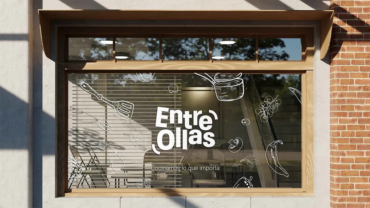 Vinilo de ventana con la identidad de la marca Entre Ollas e ilustraciones de utensilios y alimentos, de Marina Gabilondo Calleja, alumna de Diseño Gráfico y Motion Graphics en TRAZOS