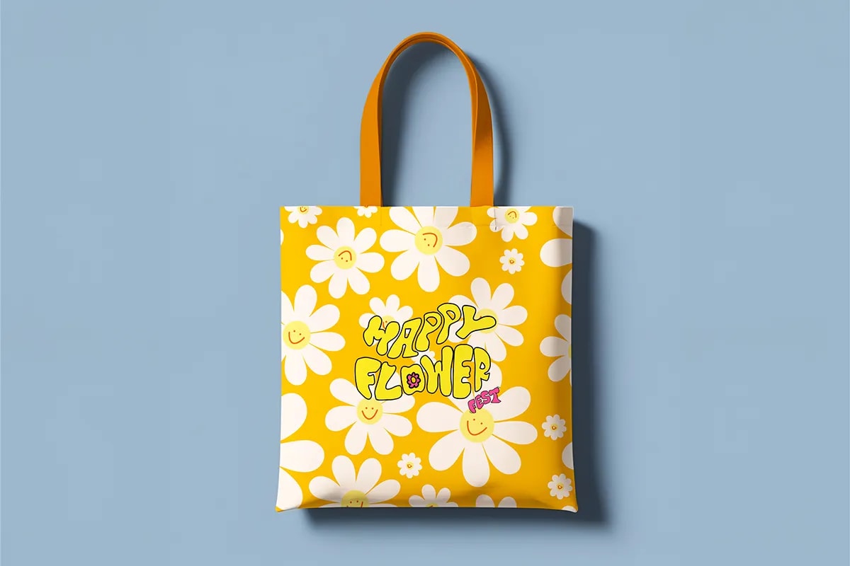Bolsa tote amarilla de Happy Flower Fest con margaritas y el logotipo, de Sofía Villalta, alumna de Diseño Gráfico y Motion Graphics en TRAZOS