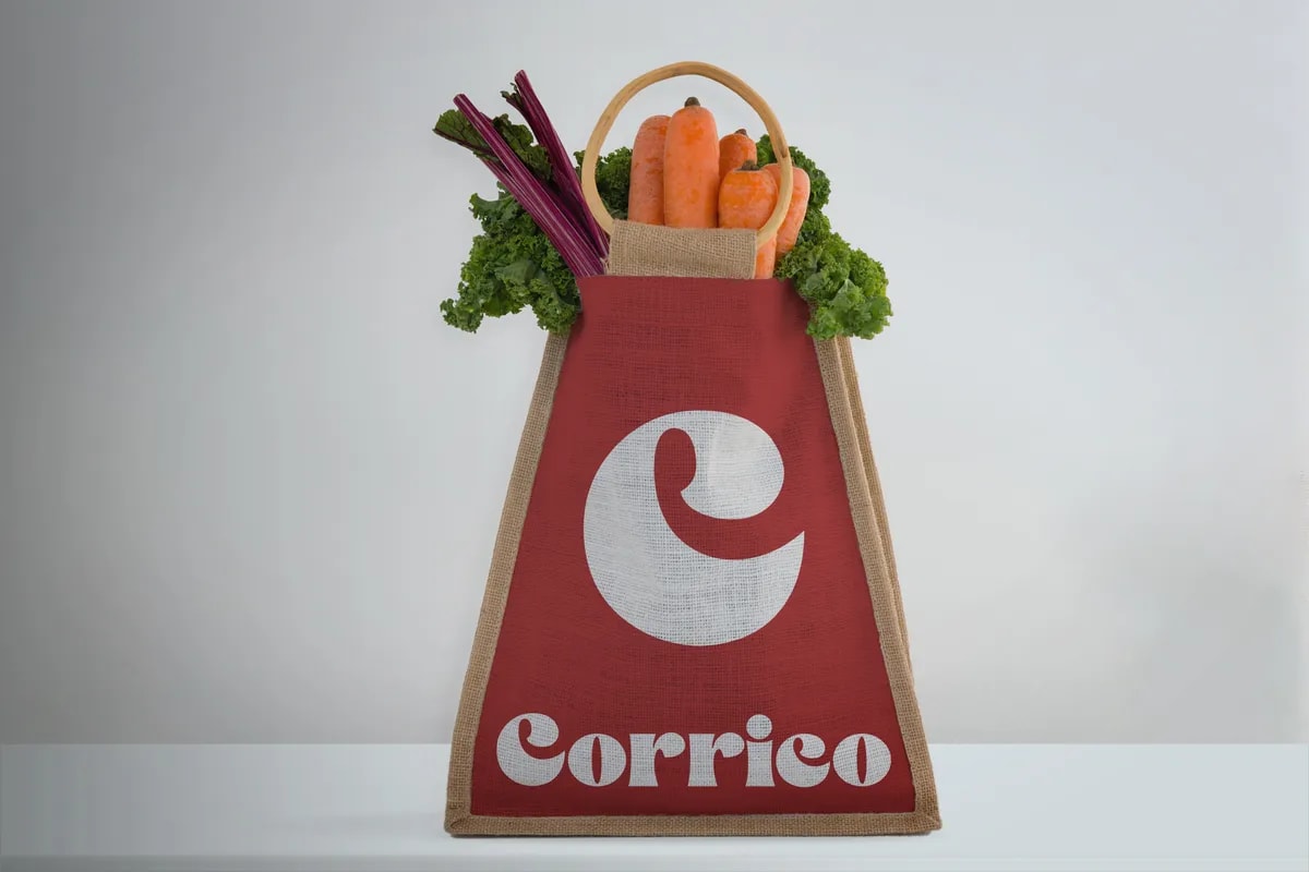 Bolsa de tela roja con el logotipo de Corrico llena de verduras, de Luis Fernández Gregorio, alumno de Diseño Gráfico y Motion Graphics en TRAZOS