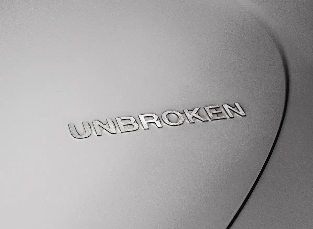 Logotipo Unbroken grabado en relieve sobre una superficie metálica gris, de María Delgado, alumna de Diseño Gráfico y Motion Graphics en TRAZOS