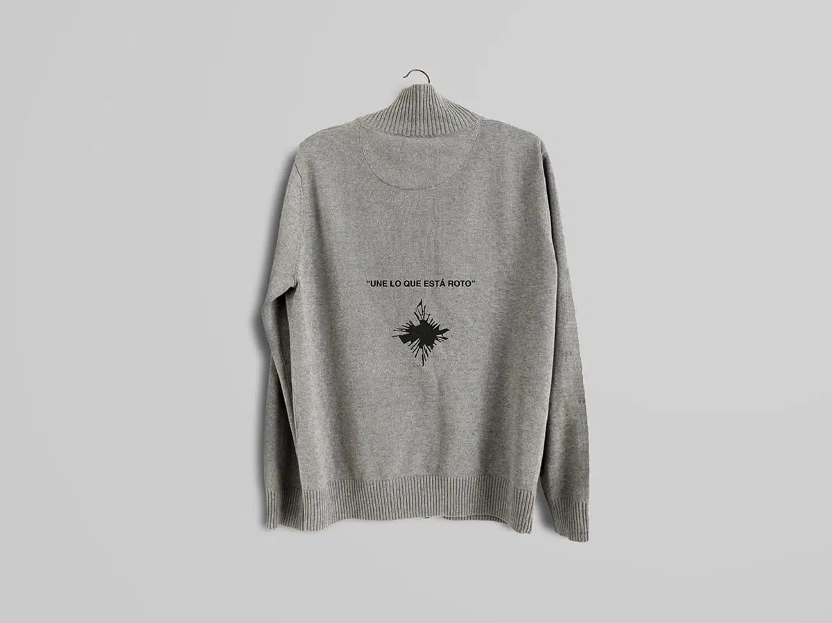 Jersey gris con la frase Une lo que está roto y un símbolo roto en la espalda, de María Delgado, alumna de Diseño Gráfico y Motion Graphics en TRAZOS