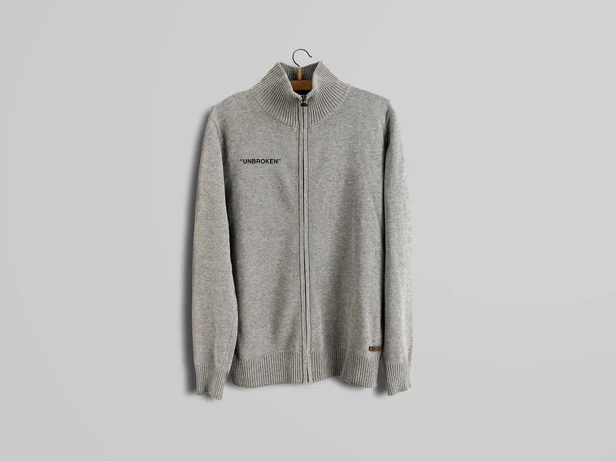 Chaqueta de punto gris con cremallera y el texto Unbroken en el pecho, de María Delgado, alumna de Diseño Gráfico y Motion Graphics en TRAZOS